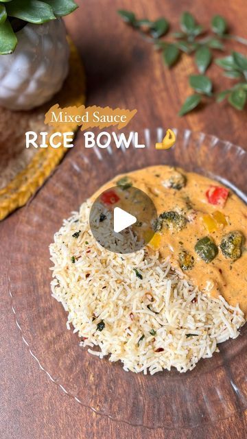 a bowl filled with rice and vegetables on top of a wooden table next to a plant