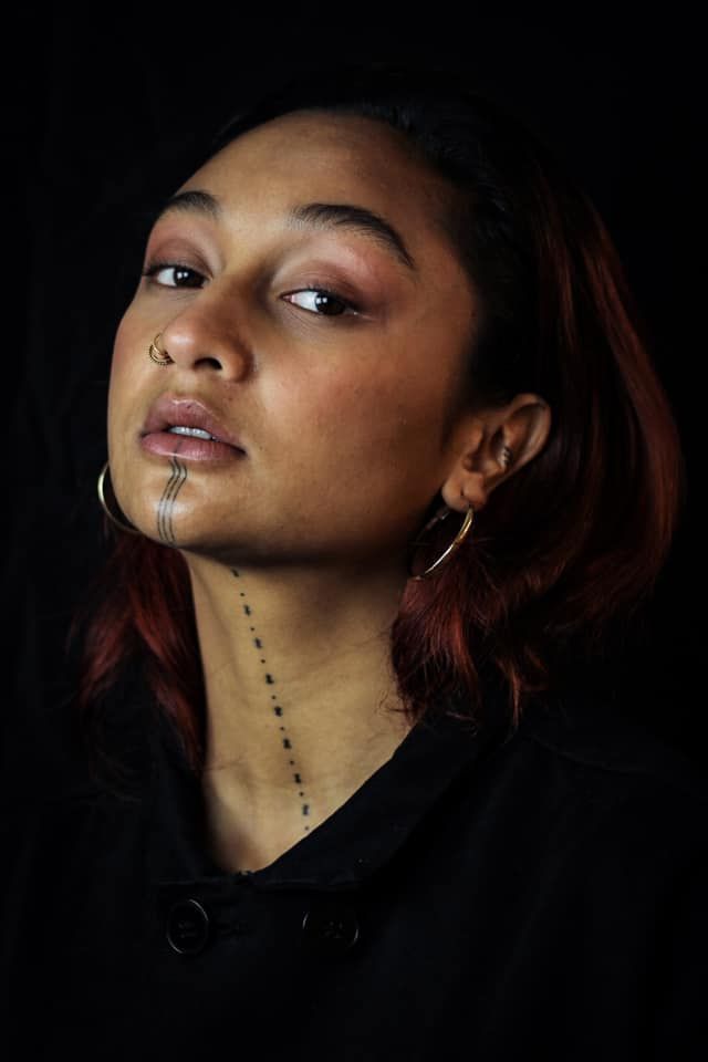 a woman with red hair and piercings on her nose looking up at the sky