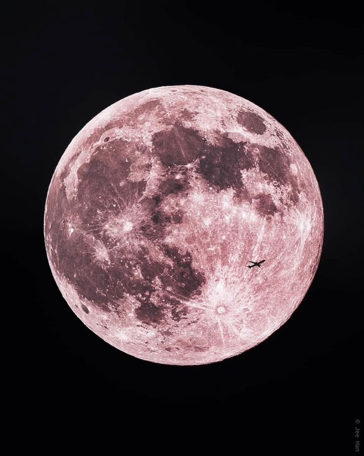 an airplane is flying in front of the full moon