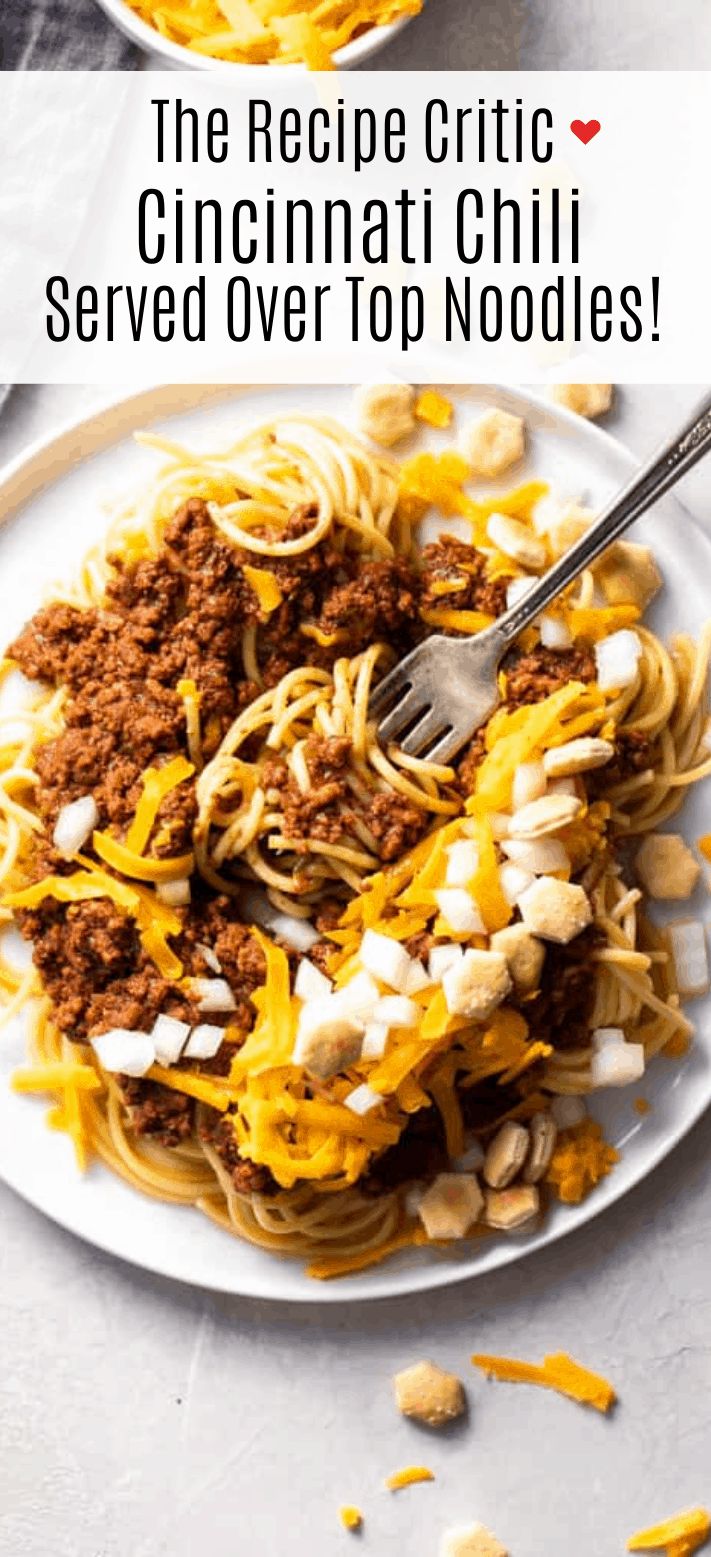 a white plate topped with noodles and cheese next to a bowl of chili sauce on the side