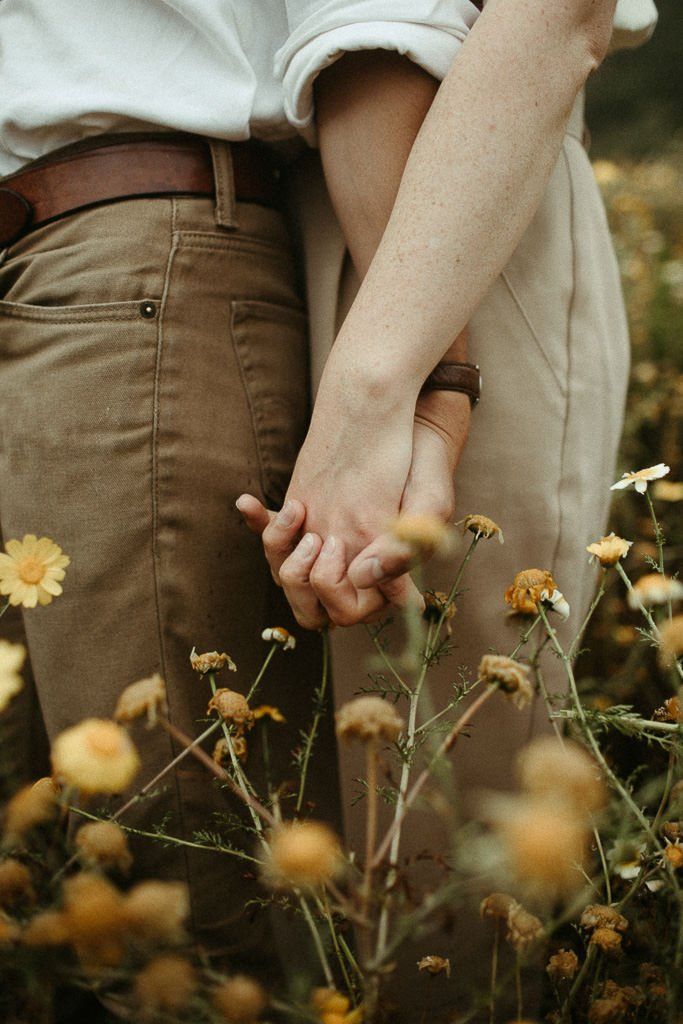 two people holding hands in a field of flowers