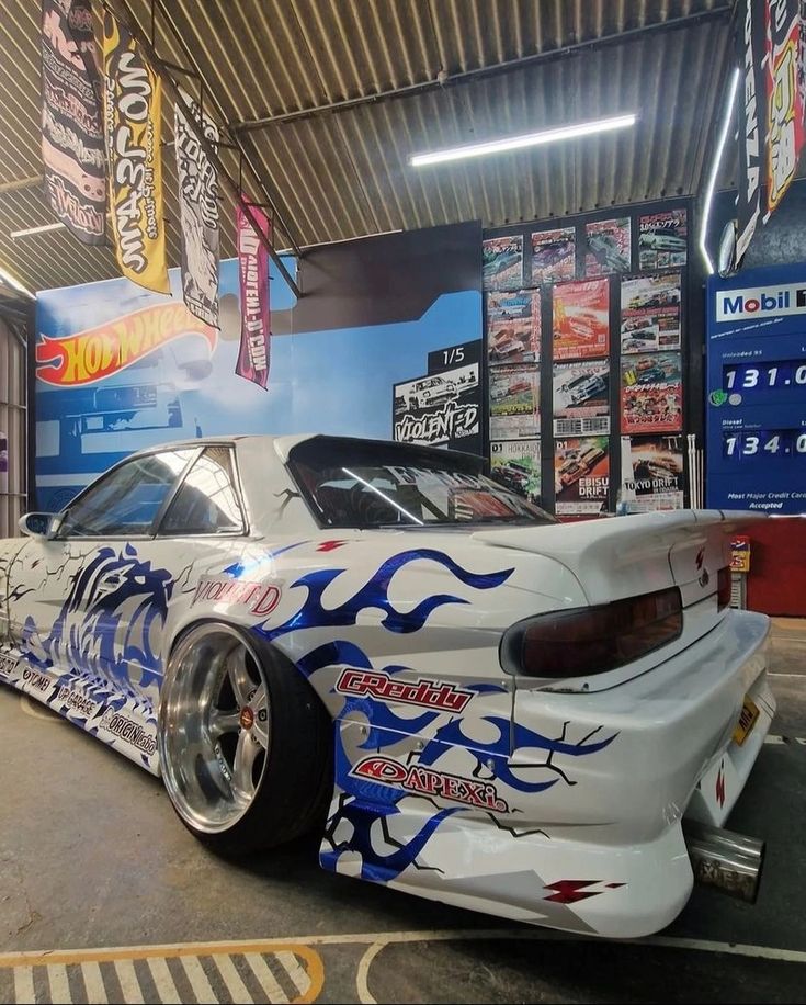 a white car with blue flames painted on it's side parked in a garage