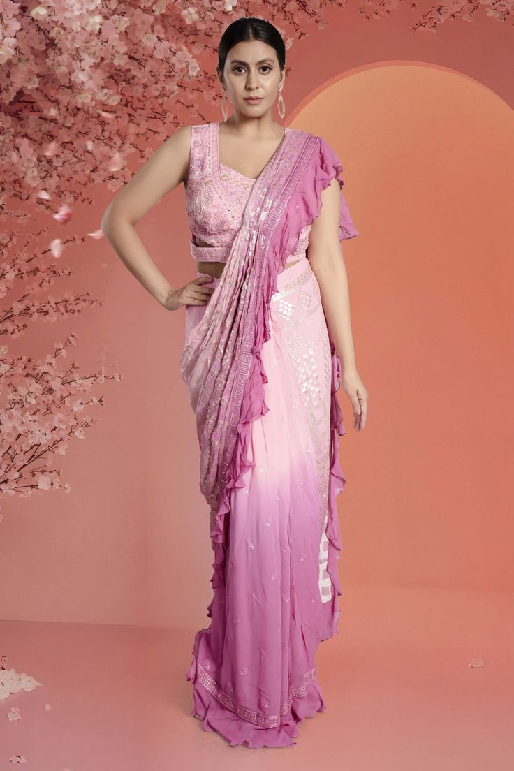 This pre-stitched saree comes with a readymade blouse featuring intricate cutdana, mirror, and stone work. The saree itself is adorned with beautiful sequence work. Effortlessly stylish and convenient, this saree will elevate your traditional look. Ombre Saree, Stitched Saree, Indian Wedding Outfit, Traditional Look, Sequence Work, Readymade Blouse, Stone Work, Pink Ombre, Wedding Outfit