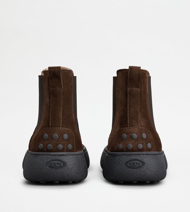 Characterized by a chunky but at the same time sober and refined outsole, the Tod's W. G. style is here proposed in Chelsea boot version. Crafted in velvety suede, with iconic rubber pebbles on the bottom and heel, they are enhanced by Tod's monogram stamped on the front. Luxury High-top Boots With Rubber Sole, Luxury Calf Leather Chelsea Boots With Lug Sole, Casual Calf Leather Boots With Vibram Sole, Luxury Chelsea Boots With Lug Sole In Calf Leather, Modern Leather Boots With Studded Outsoles, Classic Leather Boots With Studded Rubber Outsoles, Luxury Boots With Textured Sole And Round Toe, Casual Calf Leather Boots With Textured Sole, Casual Calf Leather Boots With Contrast Sole