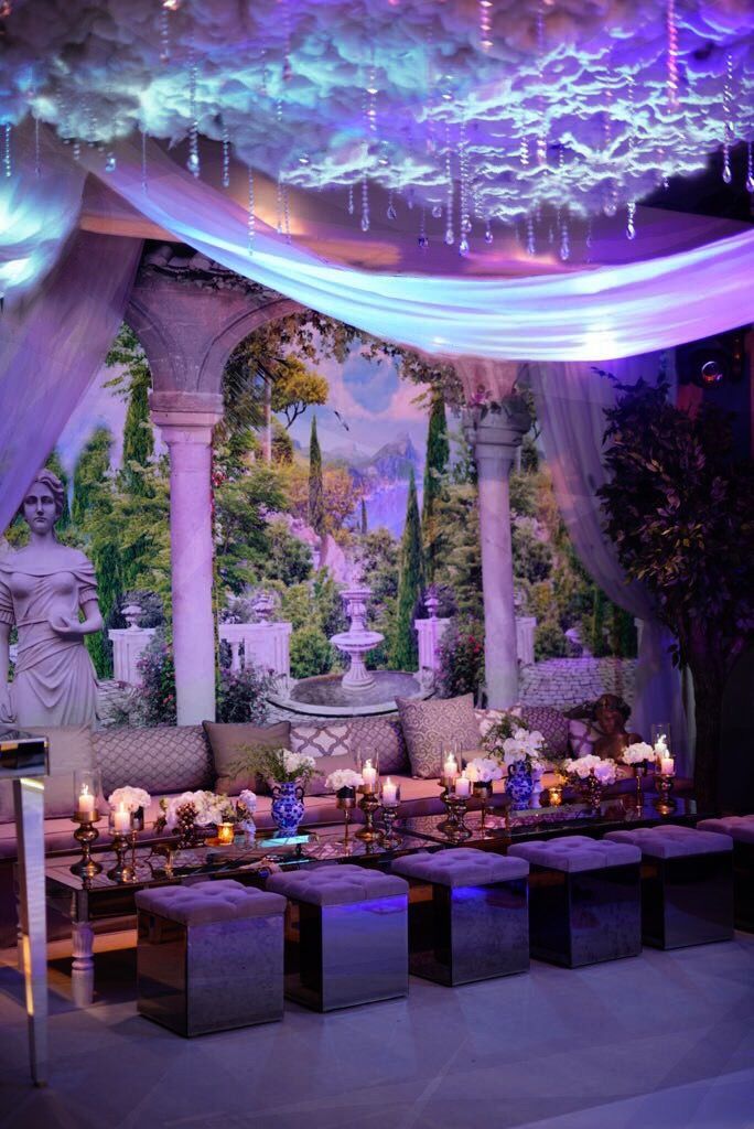 a banquet table with candles lit up in front of a large painting on the wall