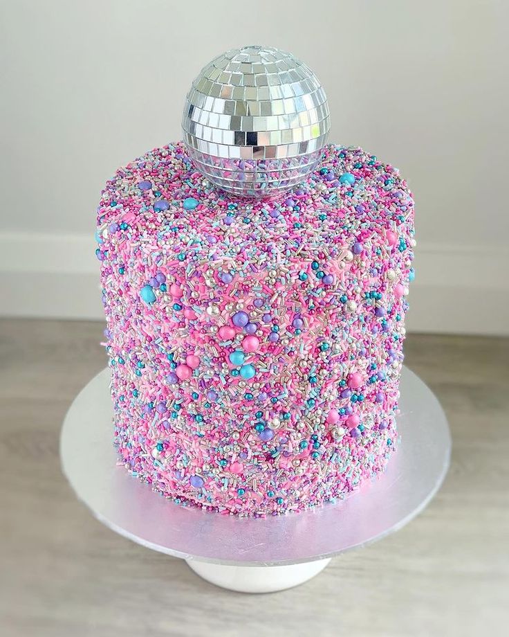 a cake with pink and blue sprinkles on it sitting on a plate