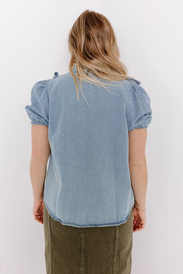 - Stay casual-cool with this ruffled denim top! - Unlined non-stretch denim material - A v-cut neckline - A buttoned front - A ruffle detailed bodice - Short sleeves with elastic cuffs - A relaxed silhouette that ends in a straight hemline Medium Wash Ruffled Tops For Summer, Washed Chambray Short Sleeve Tops, Light Wash Fitted Ruffle Top, Summer Ruffled Medium Wash Tops, Medium Wash Cotton Blouse For Day Out, Light Blue Chambray Tops For Spring, Casual Light Wash Tencel Tops, Spring Light Blue Chambray Tops, Summer Light Wash Denim Blouse