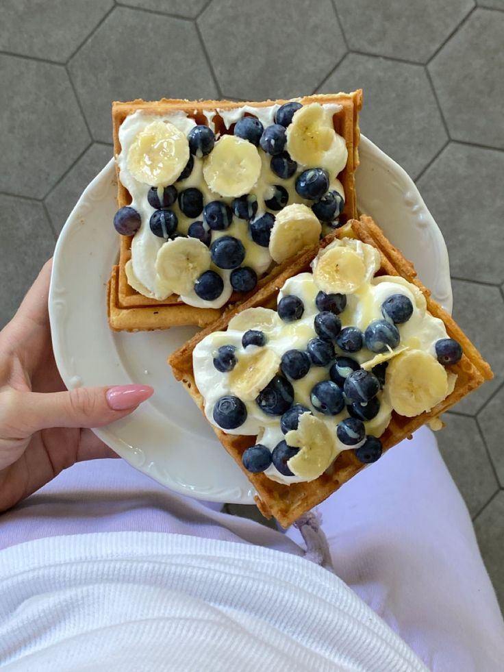 two pieces of toast with bananas and blueberries on them, sitting on a plate