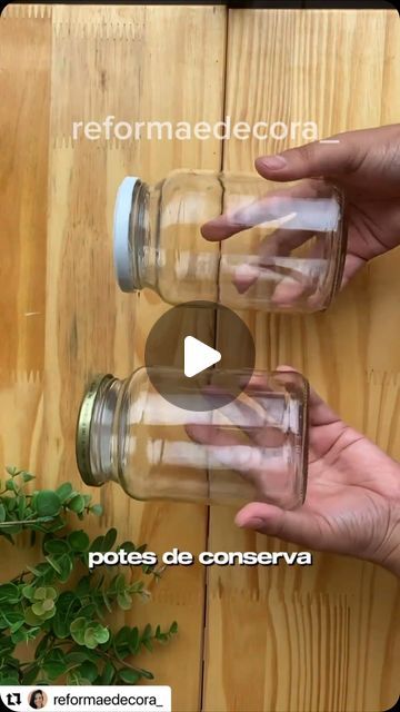 two hands holding mason jars on top of a wooden table