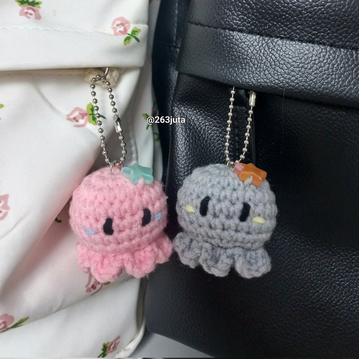 two crocheted keychains sitting next to each other on a black bag