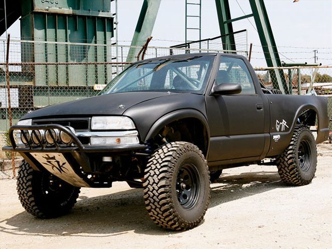 a black truck parked on top of a dirt field