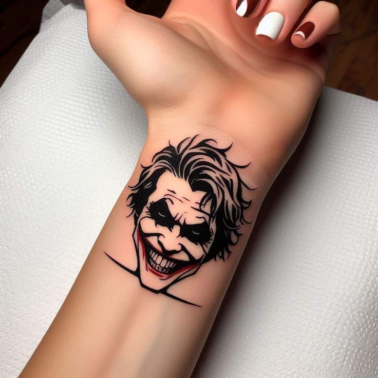 a woman's arm with a tattoo of the joker on her left wrist and an evil face