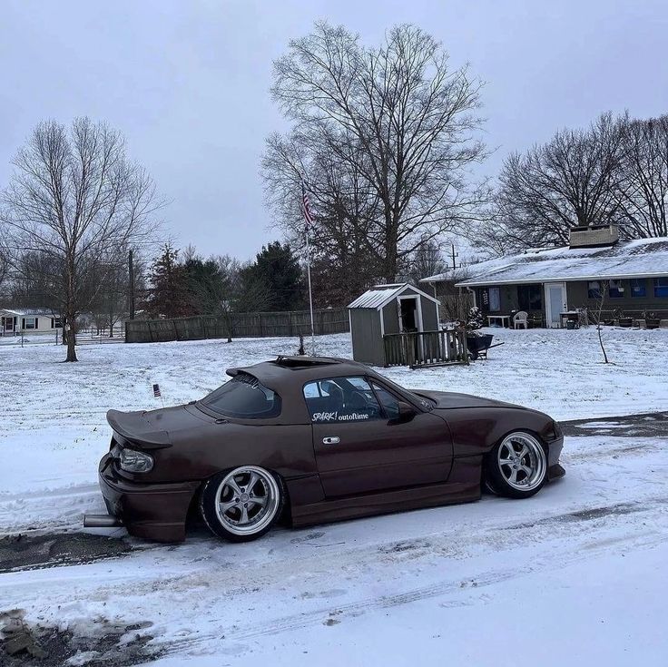 a brown car parked in the snow next to a house