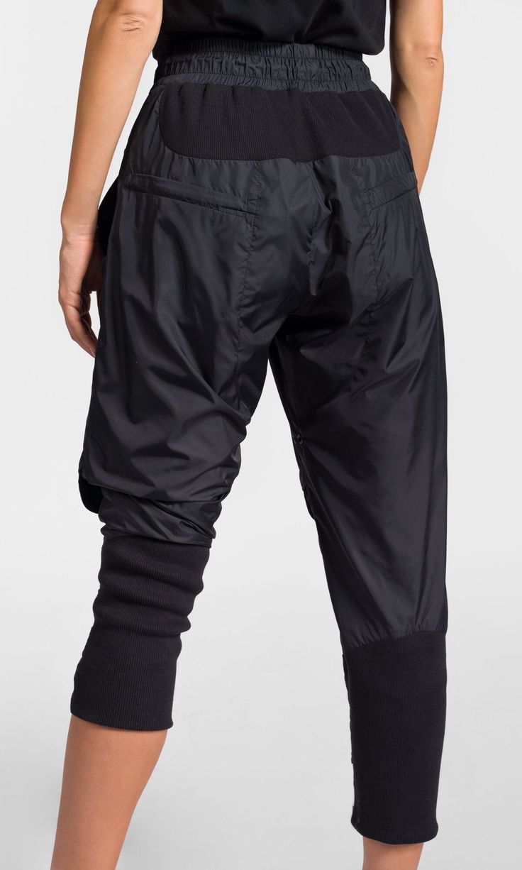 Cropped track pants with knee flap details, made of lightweight polyester fabric for a modern and comfy look. Details: * Elastic waistband with elastic drawstrings and stoppers * Front zipper closure * Decorative knee flaps * Elastic ribbed details * Two front pockets and two back zippered pockets * Calf width adjustment via Velcro patches Athleisure Full-length Parachute Pants With Side Pockets, Sporty Full-length Parachute Pants With Hip Pockets, Streetwear Ankle-length Parachute Pants With Elastic Waistband, Urban Ankle-length Parachute Pants With Side Pockets, Black Hooded Coat, Black Full-length Parachute Pants With Patch Pockets, Velcro Patches, Track Pant, Womens Trousers