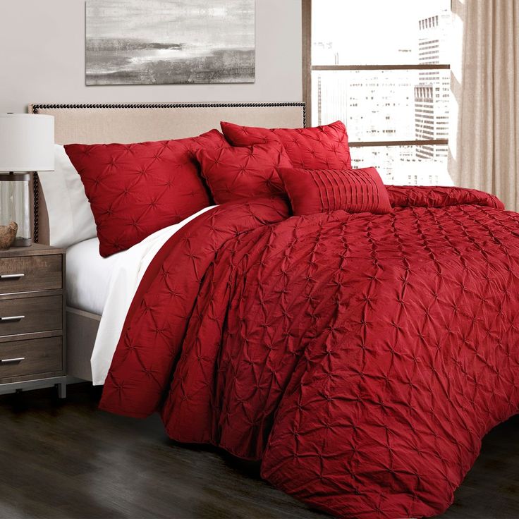 a bed with red comforters and pillows in a room