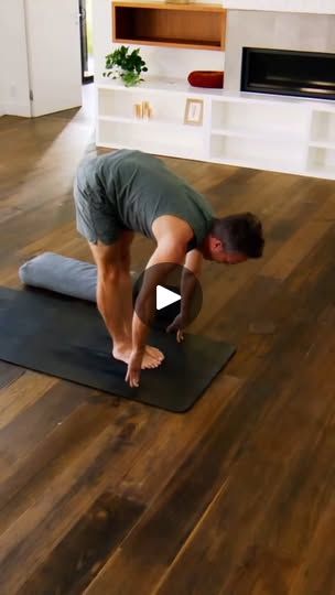 a man standing on a yoga mat in front of a fireplace