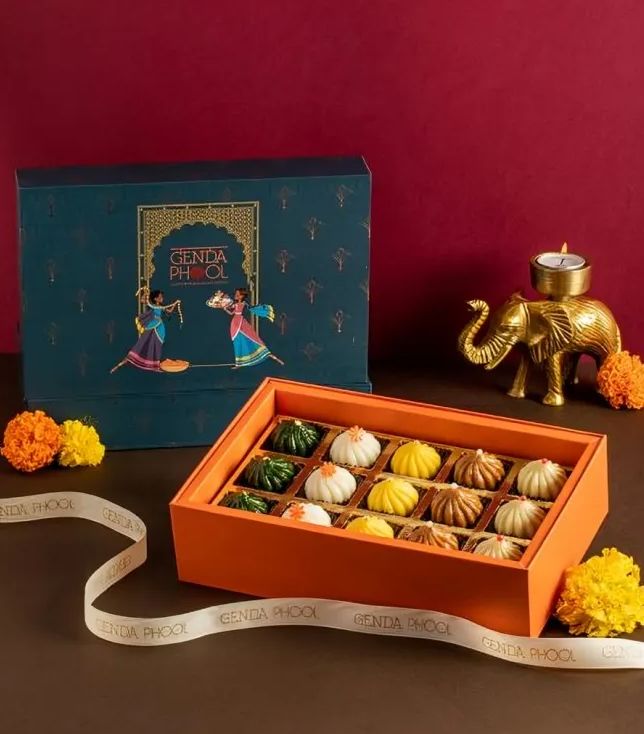 an orange box filled with miniature pumpkins on top of a table next to a ribbon