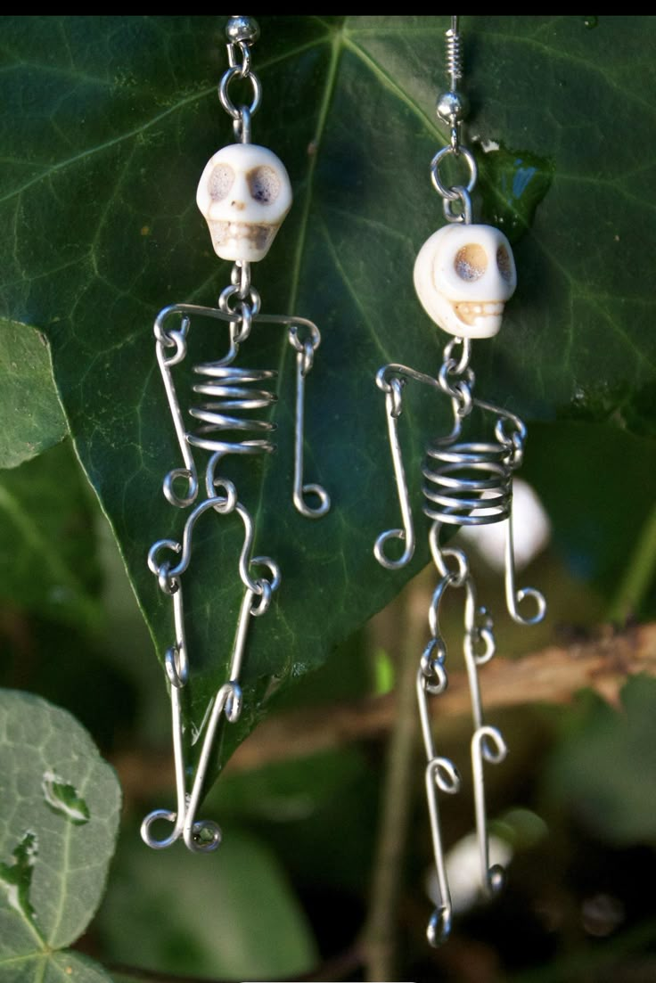 a pair of skeleton earrings with white beads hanging from it's earwires