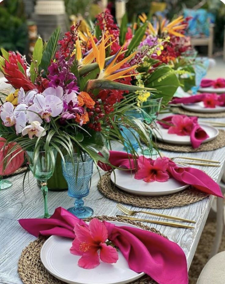 the table is set with place settings and colorful flowers in vases on each plate