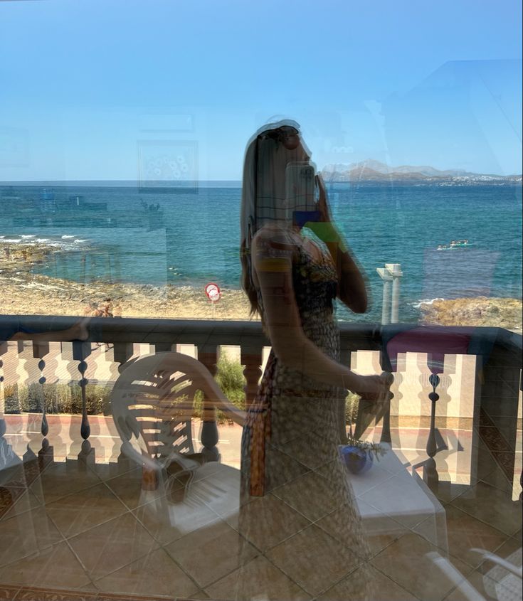 a woman standing on a balcony next to the ocean