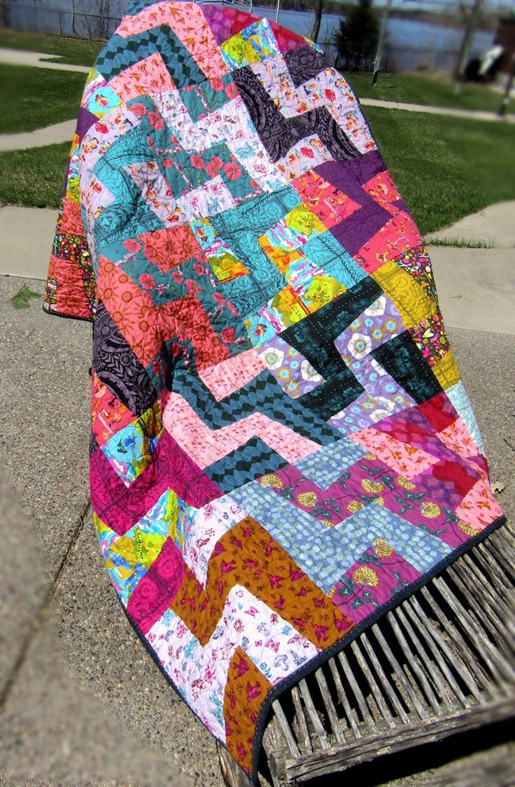 a multicolored quilt sitting on top of a metal grate next to grass