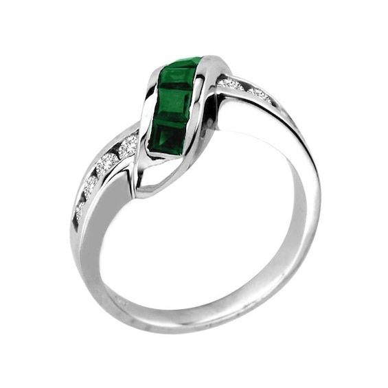 With striking elegance and subtle opulence, honor the one you love with this exquisite emerald and diamond ring. Fashioned in cool 14K white gold, this ring features an undulating wave of bright 2.6mm princess-cut green emeralds. Sparkling diamonds line the gracefully bypassing shank, completing this glamorous look. Radiant with 1/3 ct. t.w. of diamonds and polished to a lustrous shine, this ring is certain to delight the May birthday girl. Diamond Emerald Ring With Tension Setting For Anniversary, Formal Emerald Ring With Tension Setting For May Birthstone, Formal Emerald Ring With Channel Set Round Cut, Formal Emerald Diamond Ring Channel Set, Formal Channel Set Round Cut Emerald Ring, Formal Fine Jewelry Emerald Ring Channel Set, Formal Tension Setting Ring With May Birthstone, Green Diamond Channel Set Rings, Modern White Gold Emerald Rings