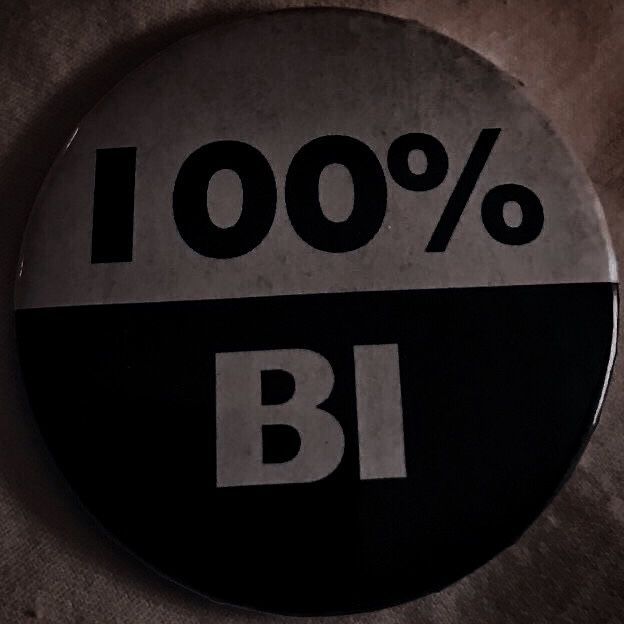 a black and white button with the words 100 % b i written in large letters