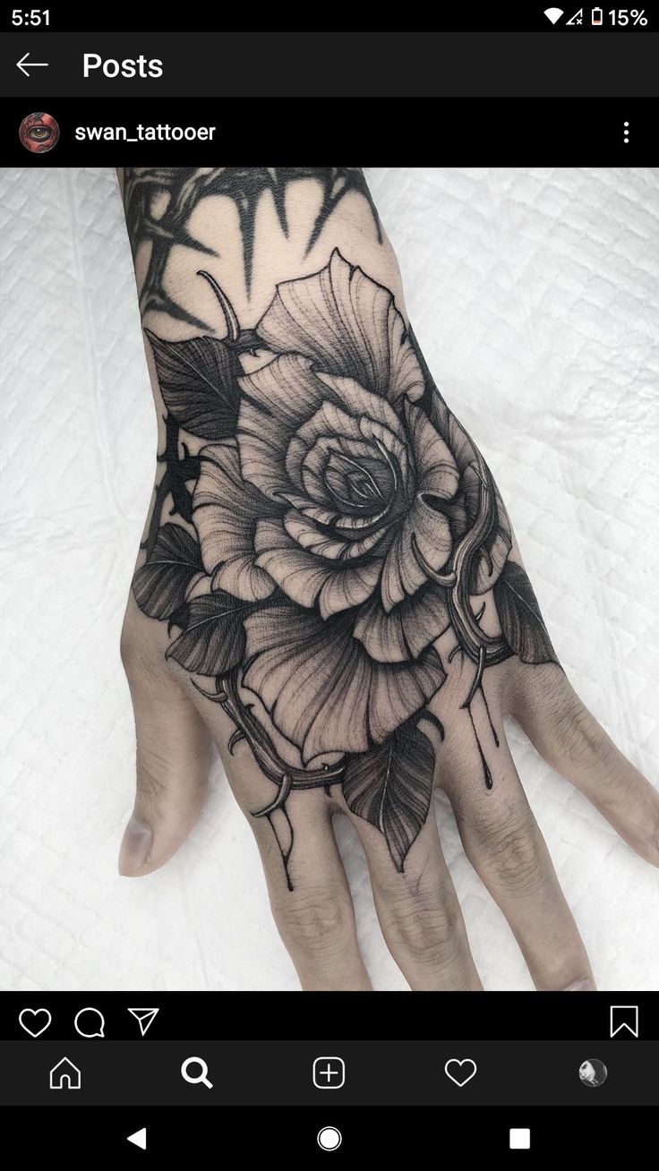 a person's hand with a black and white rose tattoo on the middle of it