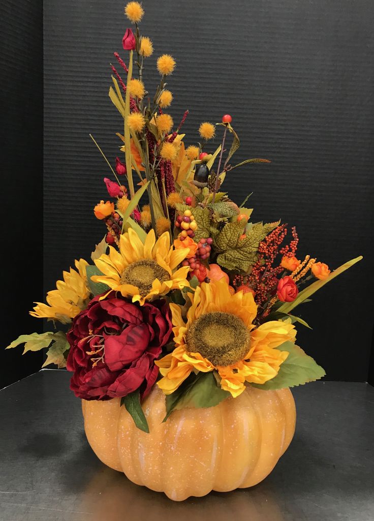 a pumpkin filled with lots of flowers on top of a table