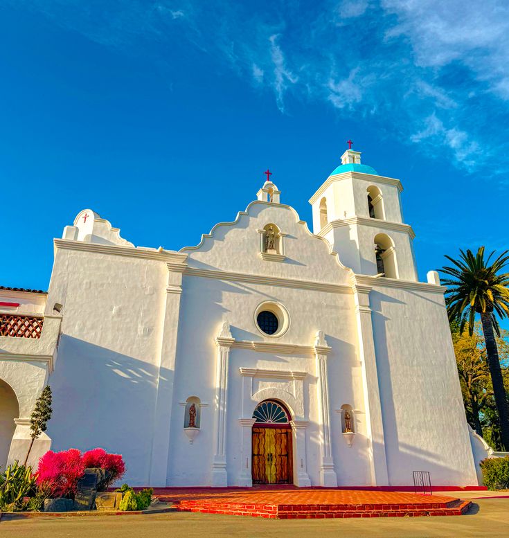 a white church with red steps and palm trees