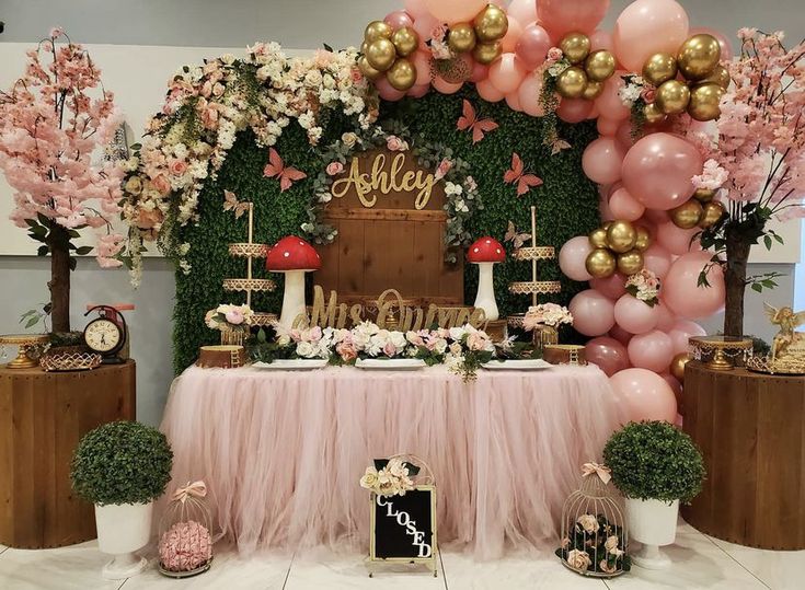 a pink and gold birthday party with balloons, flowers, cake and desserts on the table