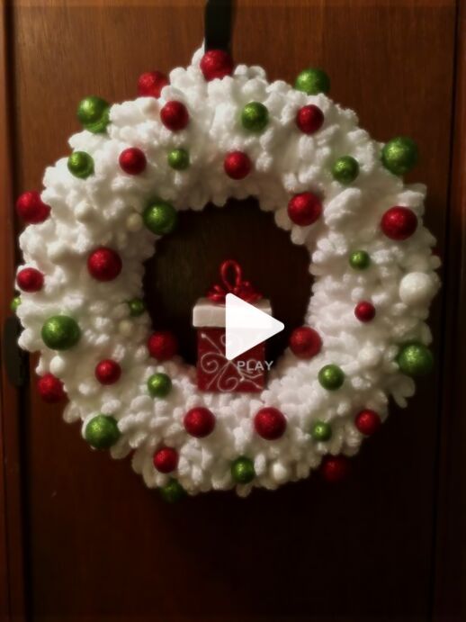 a christmas wreath hanging on a door with the word merry written in red, green and white