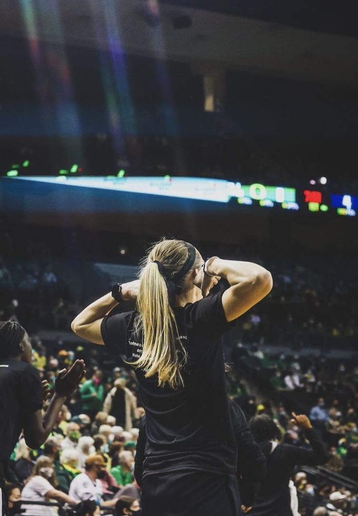 a woman standing in front of a crowd at a basketball game