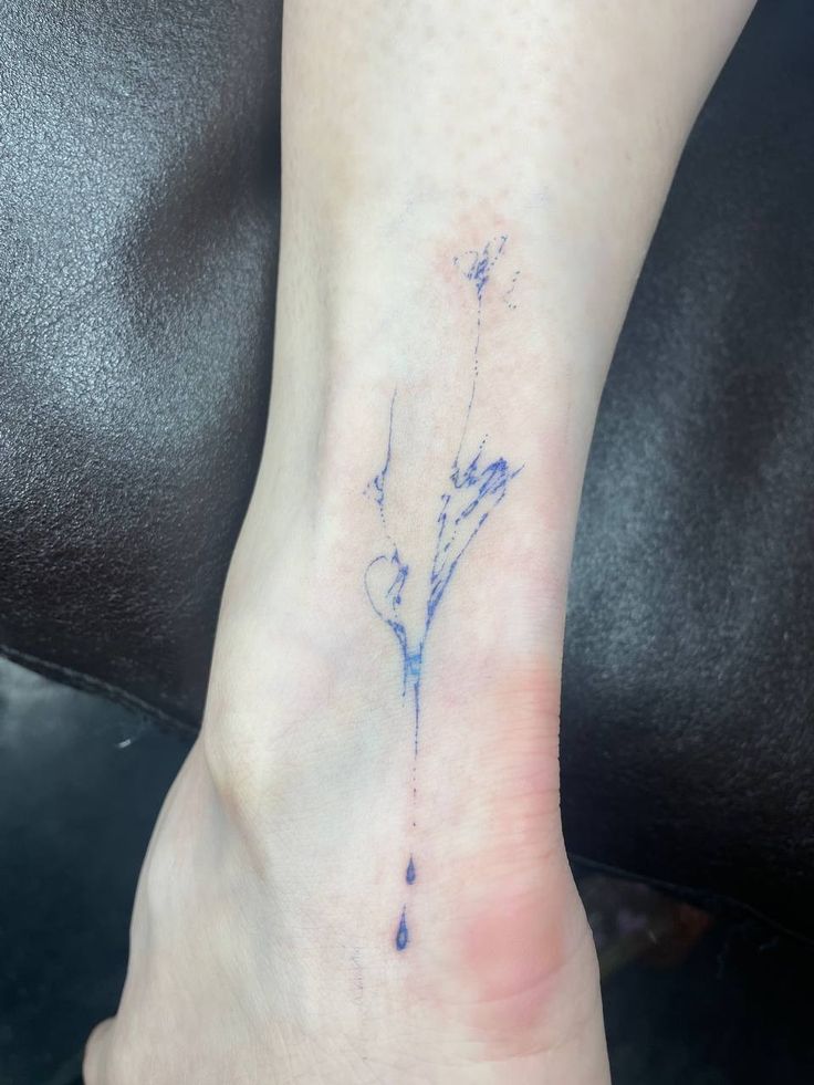 a small tattoo on the foot of a woman's foot, with blue ink