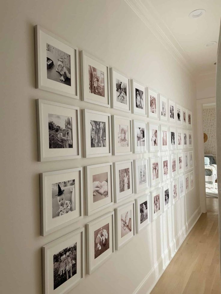 a wall with many pictures on it in a hallway next to a door and window