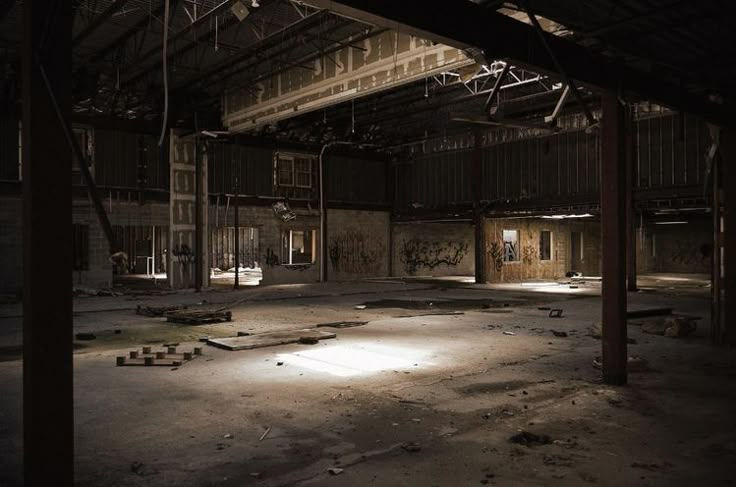 an empty warehouse with lots of graffiti on the walls and floor, all lit up at night