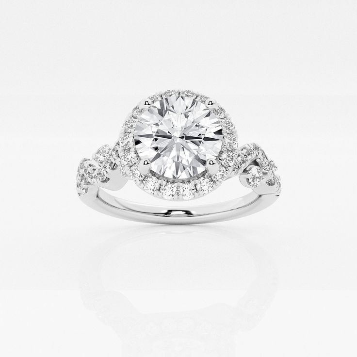 a white gold ring with diamonds on the band and an oval center stone surrounded by small round