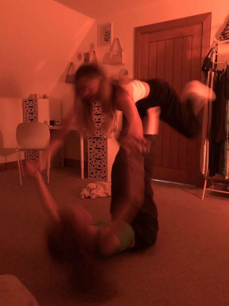 two people are dancing in a room with red light coming from the ceiling and floor