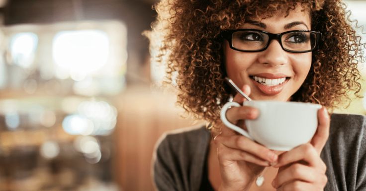 a woman with glasses holding a cup and smiling