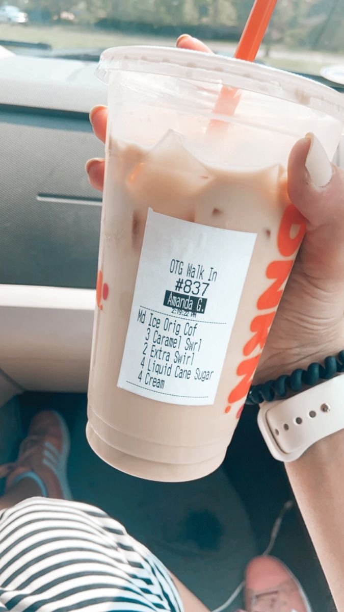 a person holding a drink in their hand while sitting in the back seat of a car