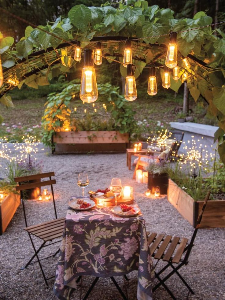 an outdoor dining area is lit up with candles and lights in the shape of mason jars