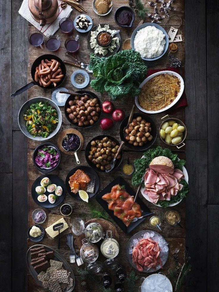 an overhead view of many different foods on a wooden table, including meats and vegetables