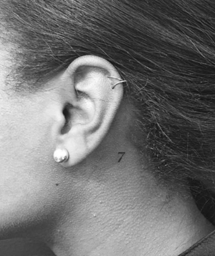 a woman's ear with an arrow tattoo on it