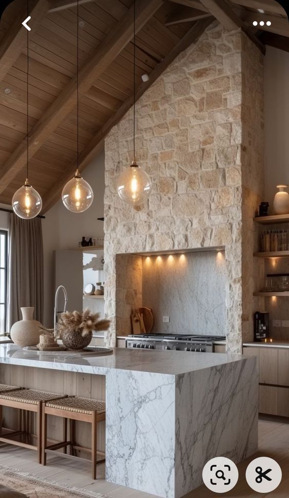 a large kitchen with an island in the middle and lights hanging from the ceiling above it