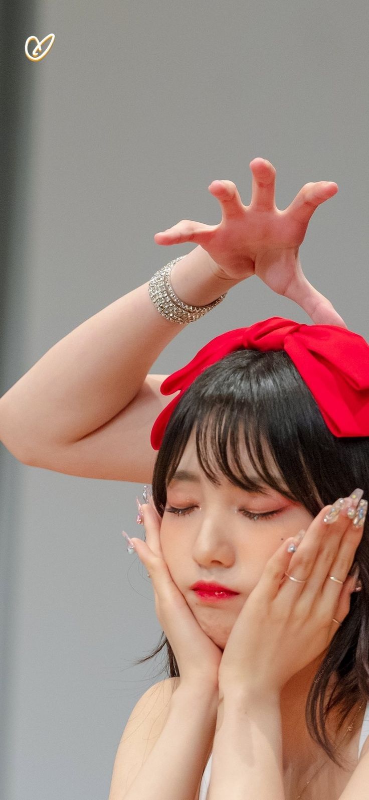 a woman with black hair wearing a red headband and holding her hands up to her face