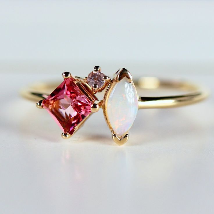 This beautiful, handmade unique cluster ring was made of 14k gold band, 14k gold prong settings. It's perfect as engagement ring or family birthstone statement piece. DETAILS ABOUT THE RING, MATERIAL AND STONES * 14k 1.3mm solid gold band and prongs. * 4x4mm princess cut natural pink tourmaline center stone * 6x3mm marquise cut real Australian opal * 1.5mm natural diamond ( 0.015 ct. weight) GH color SI clarity This ring can be personalized with the different birtstones. RING SIZE : US 7 READY TO SHIP! It can be resized in a week. ** All our raw materials are sourced from US-based companies for the quality and safety of our handmade products. *** This ring is handcrafted for you in our local studio in Redlands, California. We are a small workshop which specializes on handmade jewelry. *** 14k Gold Birthstone Cluster Ring, 14k Gold Cluster Ring With Birthstone, 14k Gold Cluster Sapphire Promise Ring, Pink 14k Gold Cluster Ring With Gemstone, Cluster Yellow Gold Birthstone Ring Gift, Birthstone Cluster Ring With Accent Stones As Gift, Yellow Gold Cluster Birthstone Ring Gift, Birthstone Cluster Ring Gift, 14k Gold Cluster Birthstone Ring