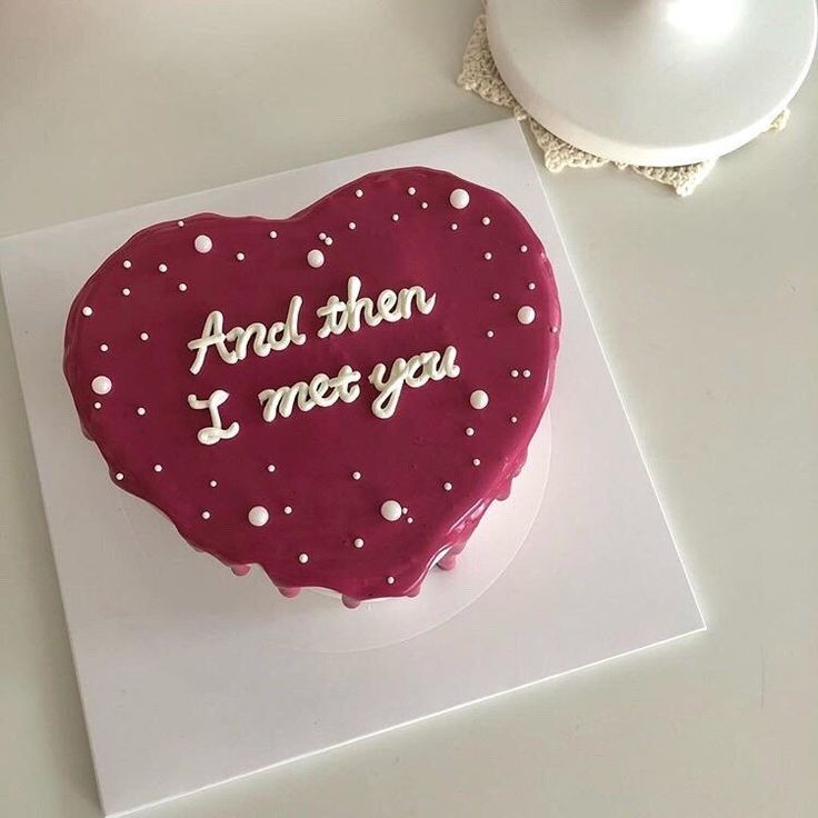 a heart shaped cake with the words and then i mot you on it next to a teapot