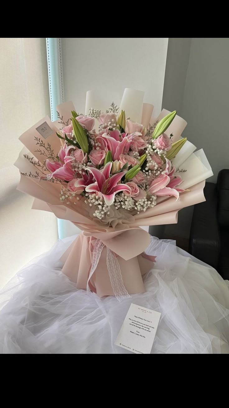 a bouquet of pink flowers sitting on top of a white table next to a window