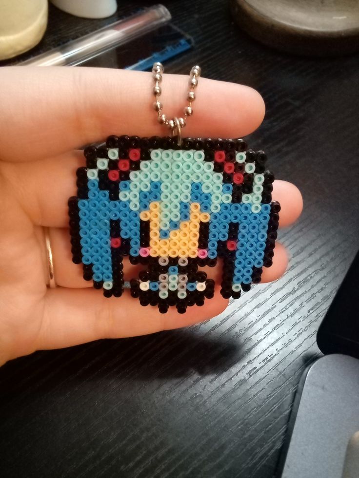 someone is holding a small pixel art keychain