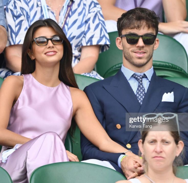 a man and woman sitting next to each other at a tennis match in the stands